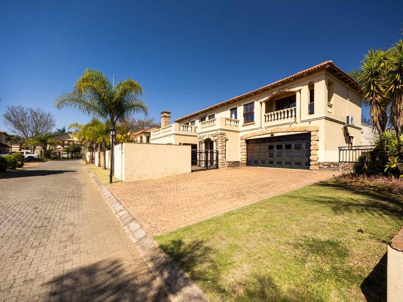 A well-maintained double-story residential property featuring a paved driveway, double garage, and an upper-level balcony with stone architectural accents.