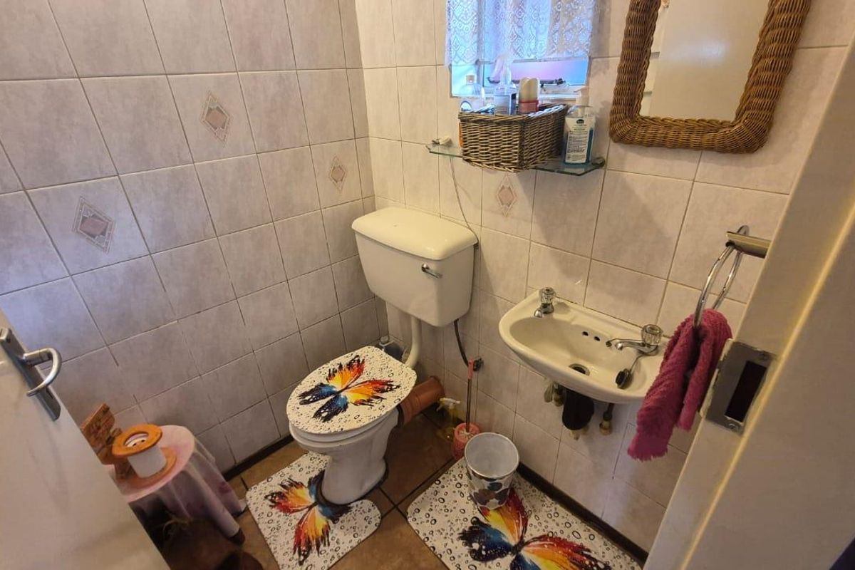 A compact guest bathroom featuring tiled walls and floors, equipped with a standard toilet and a wall-mounted basin.