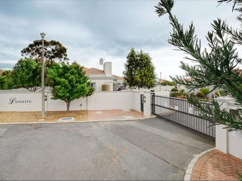 Entrance view of the Lunaire residential complex featuring a secure sliding gate, perimeter wall, and paved driveway access.
