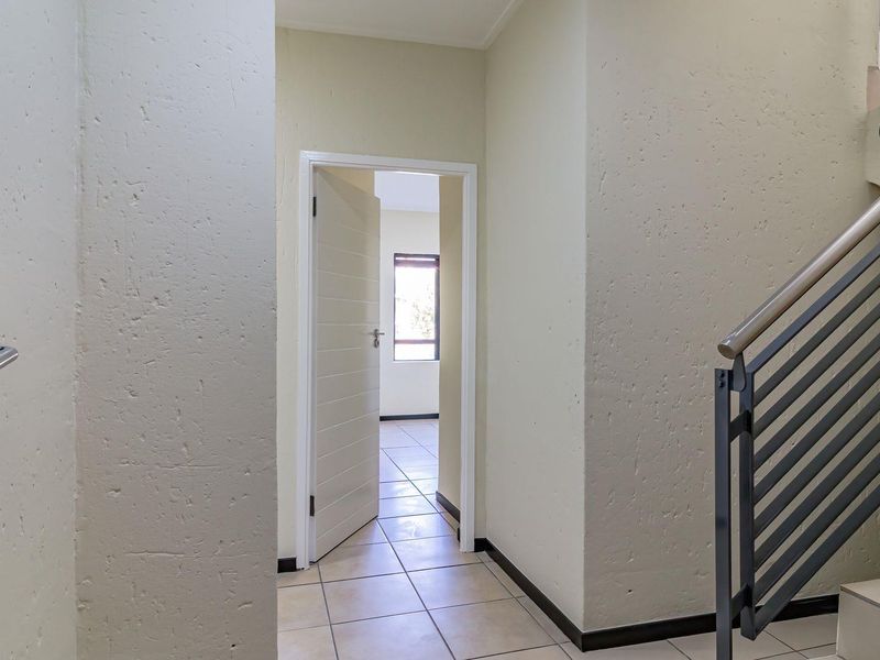 Entrance foyer featuring tiled flooring, a staircase with a metal balustrade, and access to an adjacent room.