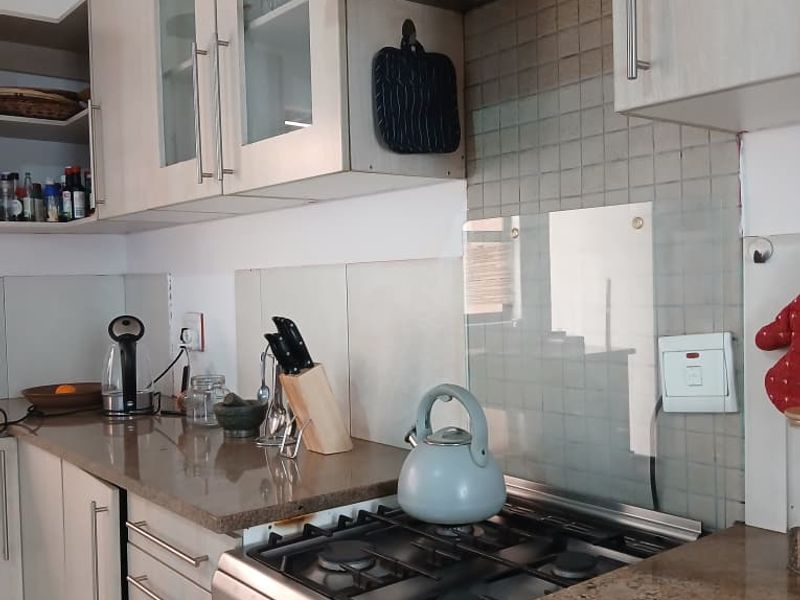 A functional kitchen featuring granite countertops, a gas stove with an extractor fan, and ample built-in cabinetry with a tiled backsplash.