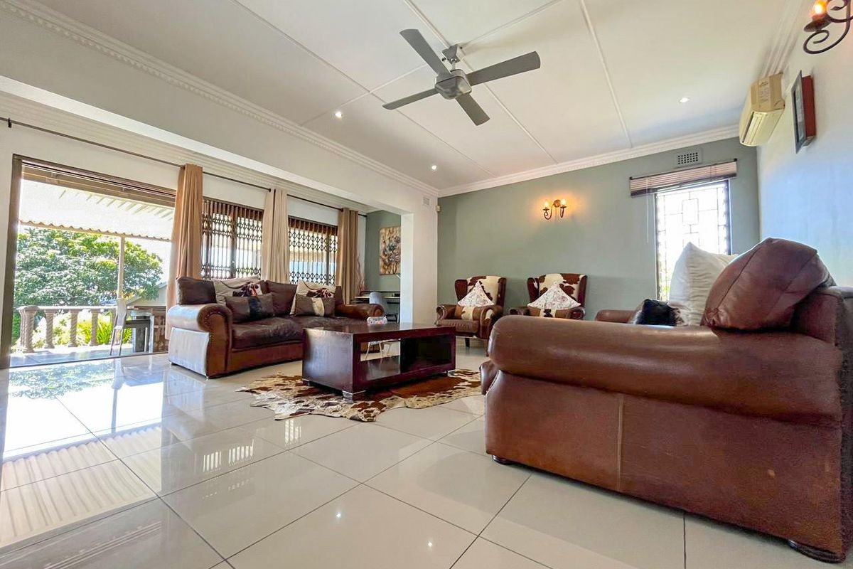 Spacious living room featuring polished floor tiles, a ceiling fan, and large sliding doors providing seamless access to the outdoor patio area.