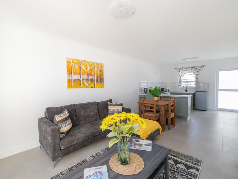 An open-plan living and kitchen area featuring neutral tiled flooring, modern cabinetry, and a subway tile backsplash in a bright, well-maintained space.