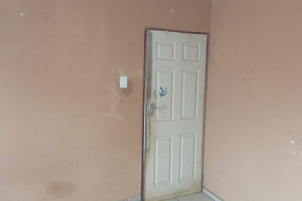 An empty room featuring plain walls and a standard interior door, requiring cosmetic updates and fresh paint to improve its overall condition.