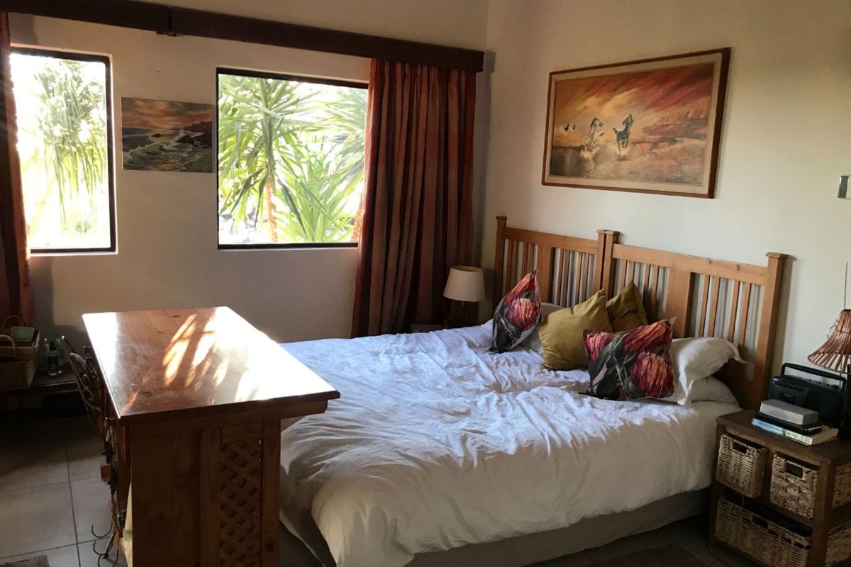 A bedroom featuring tiled flooring, large windows allowing natural light, and neutral wall finishes.