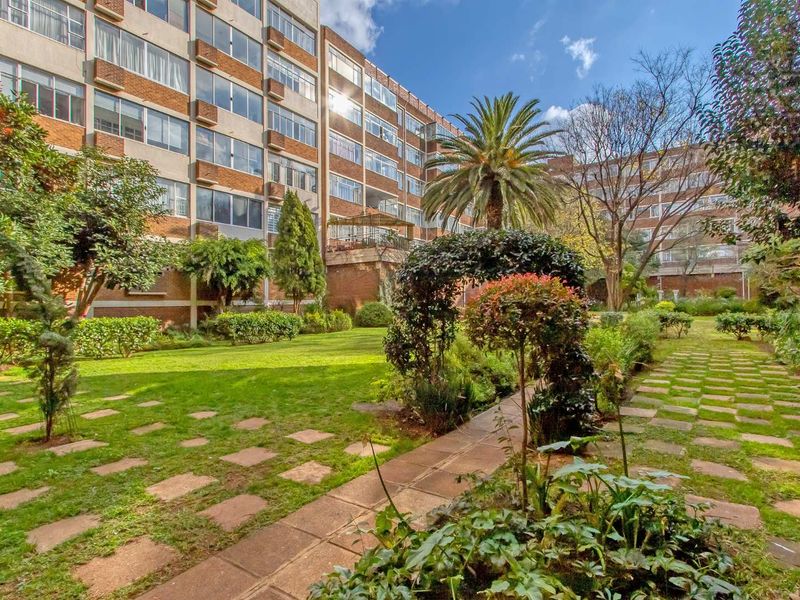 A view of the well-maintained communal garden and landscaped grounds situated between the apartment building blocks.