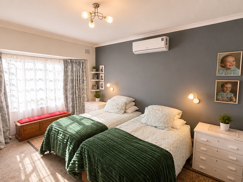 A well-maintained bedroom featuring a split-system air conditioner, neutral wall finishes, and ample natural light through a large window.