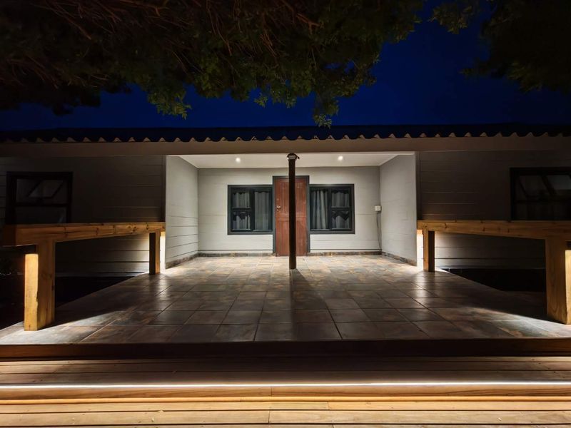 A well-lit covered patio area featuring tiled flooring, timber decking, and integrated accent lighting, creating an inviting outdoor space.