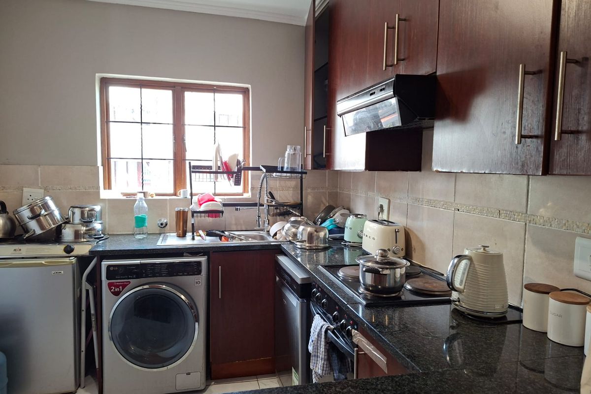 A functional kitchen featuring dark wood cabinetry, granite countertops, a tiled backsplash, and integrated cooking and laundry appliances.