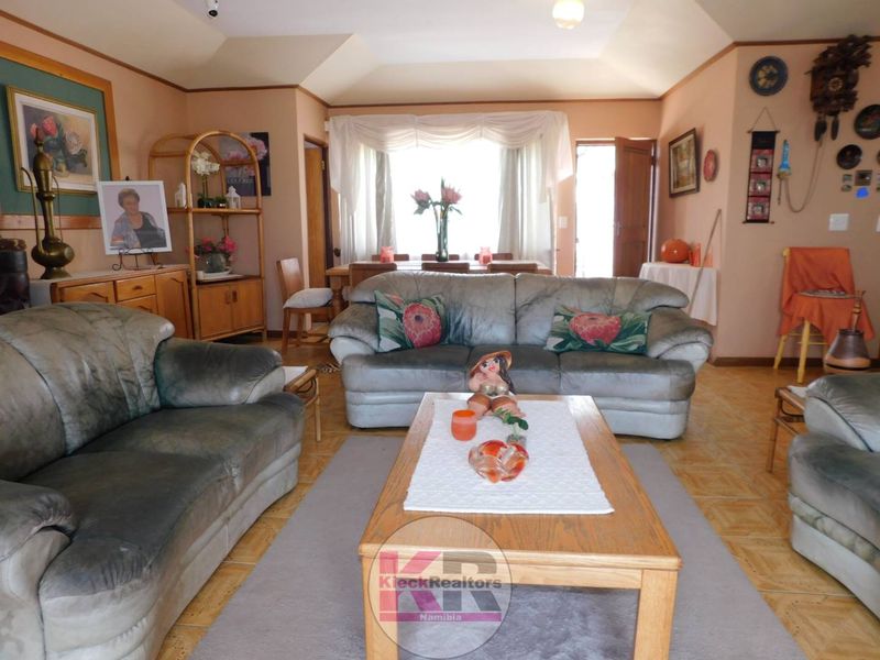 Spacious living room featuring a tray ceiling, ceramic tile flooring, and a large bay window allowing for natural light.