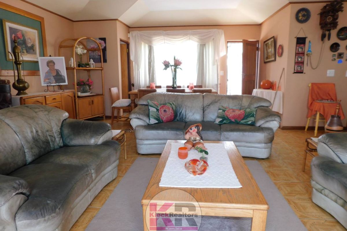 Spacious living room featuring a tray ceiling, ceramic tile flooring, and a large bay window allowing for natural light.
