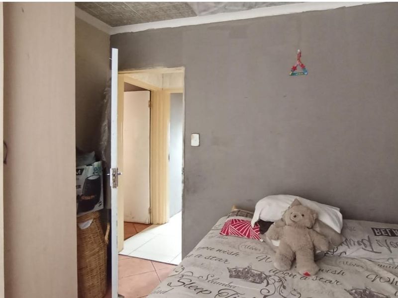 A bedroom featuring a built-in wardrobe and textured ceiling tiles, currently requiring wall finishing and cosmetic updates to improve the overall aesthetic.