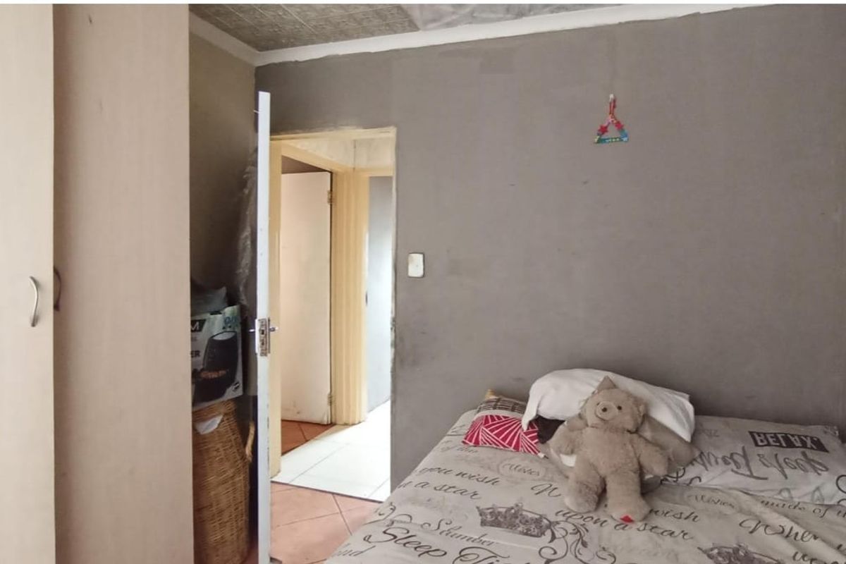 A bedroom featuring a built-in wardrobe and textured ceiling tiles, currently requiring wall finishing and cosmetic updates to improve the overall aesthetic.