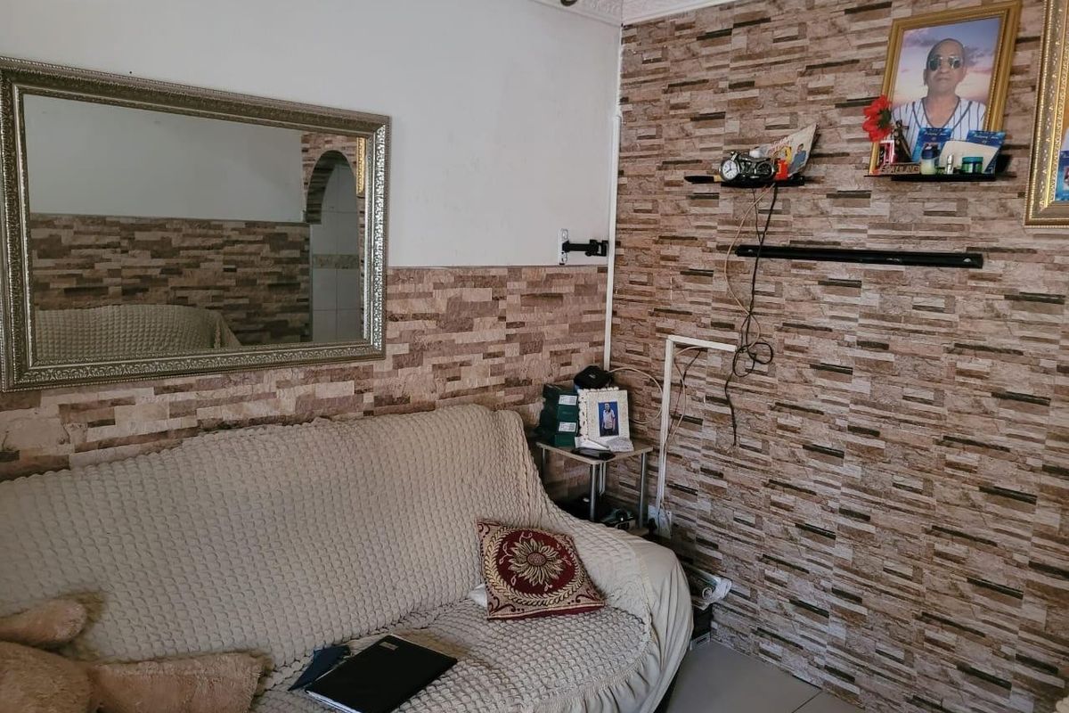 Living room featuring decorative stone-effect wall cladding, tiled flooring, and coving, providing a base for potential cosmetic updates.