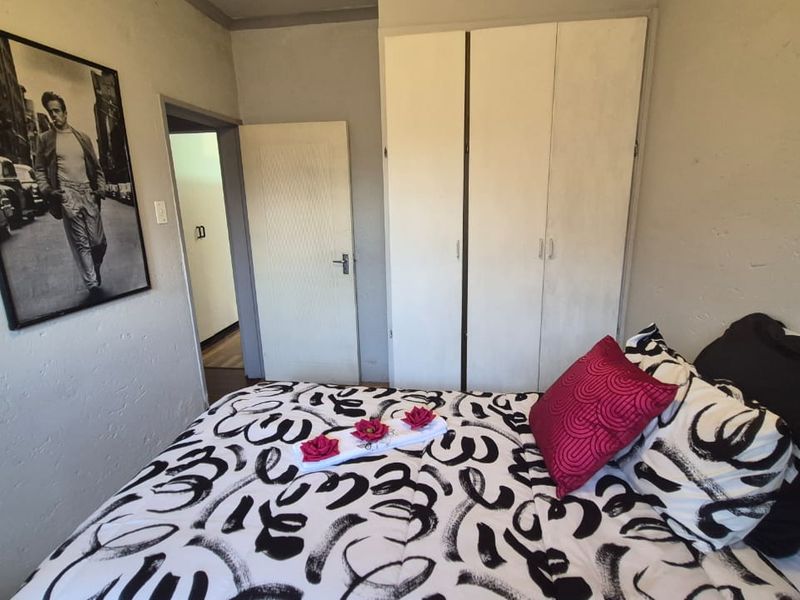 A functional bedroom featuring built-in wardrobe storage and neutral wall finishes, offering a practical space for rest.