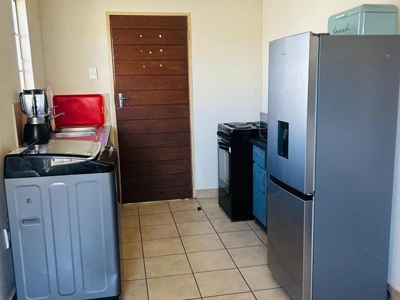 A functional kitchen area featuring tiled flooring, built-in cabinetry, and a freestanding stove, providing a practical space for meal preparation.