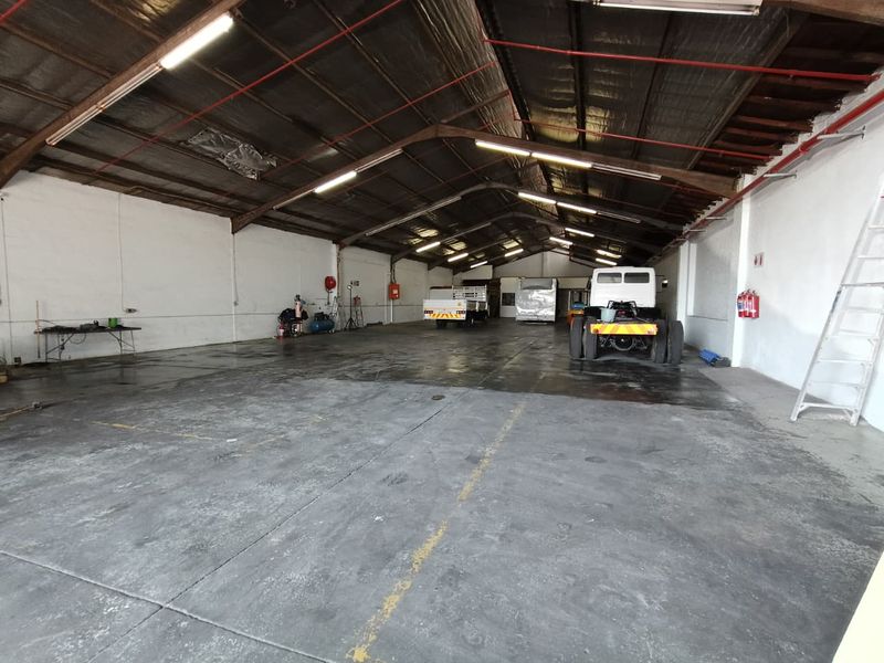 Spacious industrial utility area featuring high ceilings with exposed steel trusses, concrete flooring, and integrated fire safety systems.