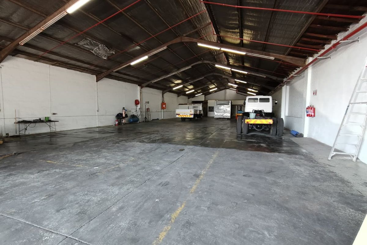 Spacious industrial utility area featuring high ceilings with exposed steel trusses, concrete flooring, and integrated fire safety systems.