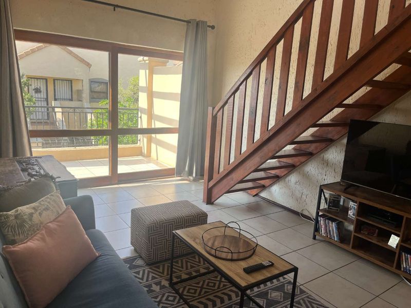 Living room featuring tiled flooring, a wooden staircase, and large sliding glass doors providing access to an outdoor balcony area.