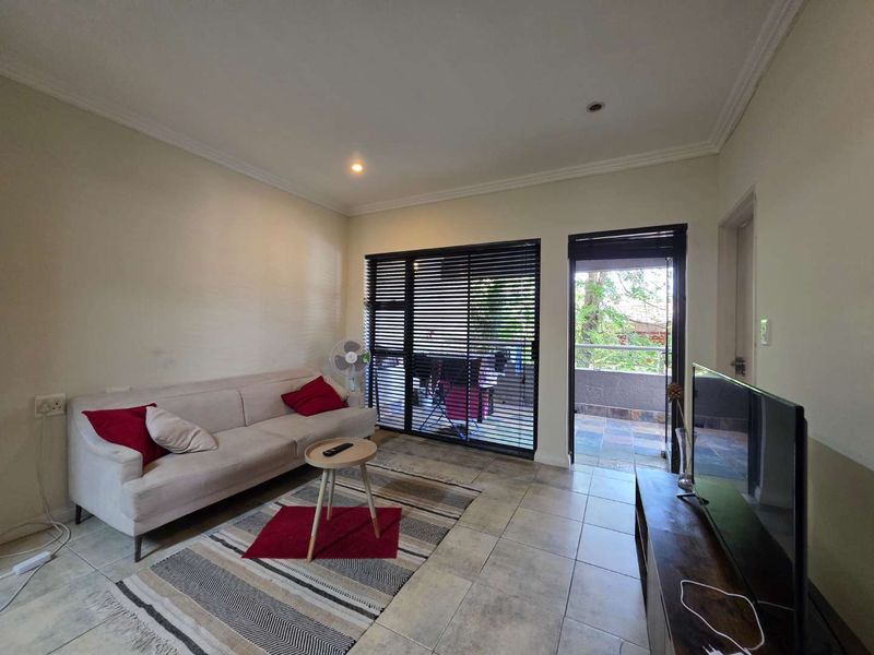 A living room featuring tiled flooring, recessed lighting, and direct access to an outdoor balcony through a sliding glass door.