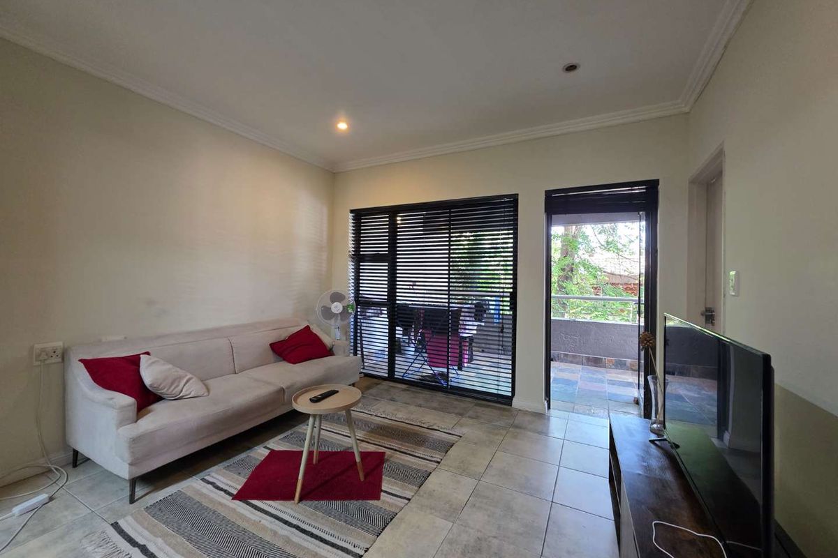 A living room featuring tiled flooring, recessed lighting, and direct access to an outdoor balcony through a sliding glass door.