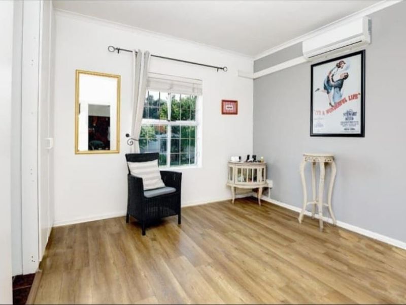 A well-maintained bedroom featuring modern laminate flooring, a split-system air conditioner, and a built-in wardrobe, offering a clean and functional living space.