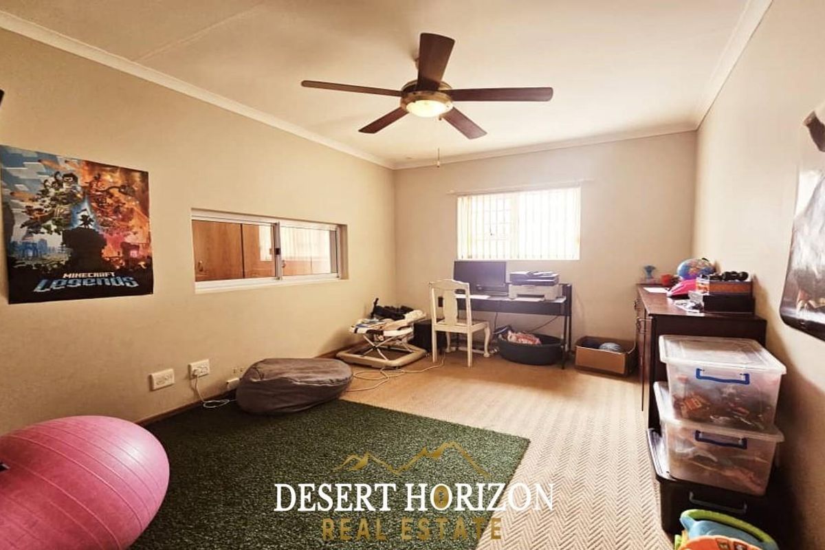 A functional bedroom featuring a ceiling fan, carpeted flooring, and dual windows providing natural light.