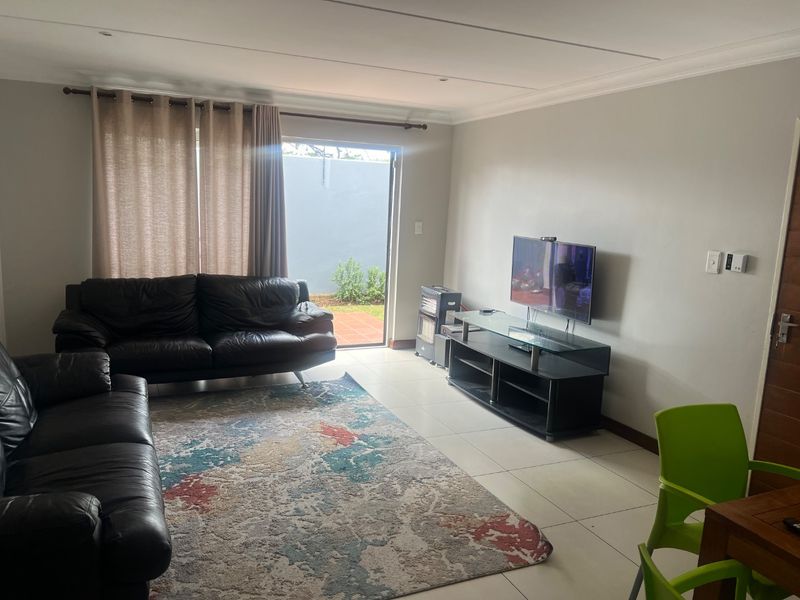 A living room featuring tiled flooring and a sliding glass door providing access to an outdoor area.