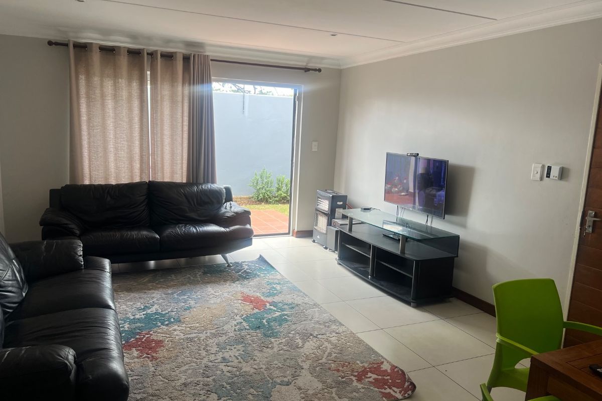 A living room featuring tiled flooring and a sliding glass door providing access to an outdoor area.