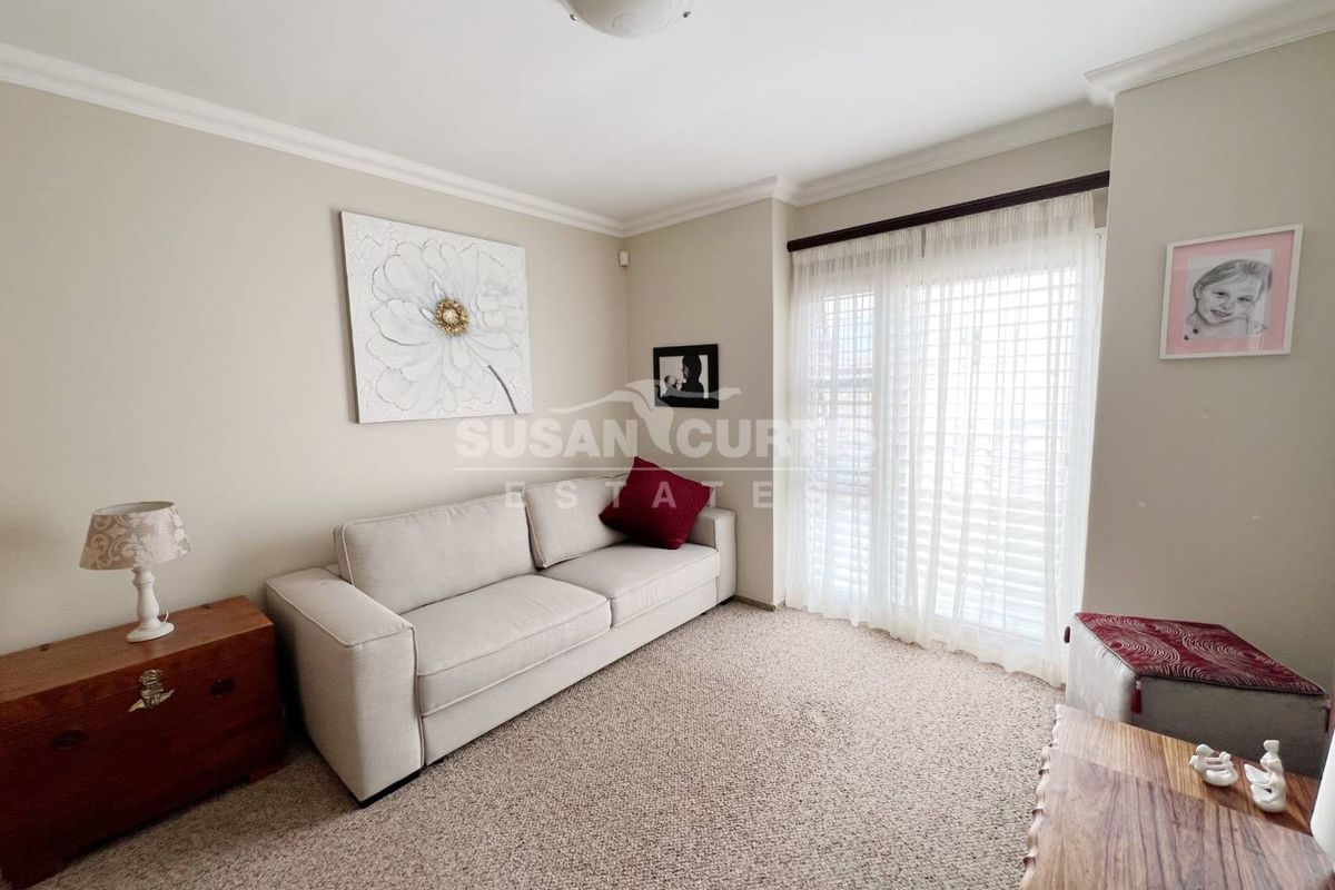 A cozy living room featuring neutral carpeting, crown molding, and sliding glass doors that provide access to the exterior.