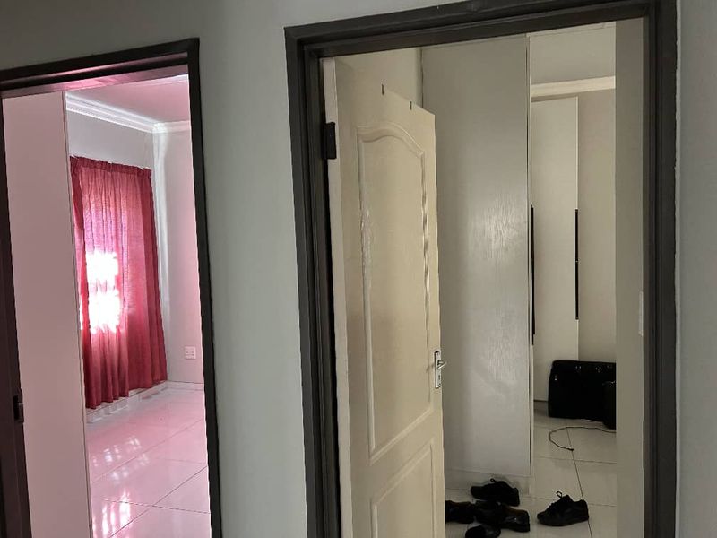 A view through a hallway showing access to adjacent rooms with tiled flooring and built-in storage cupboards.