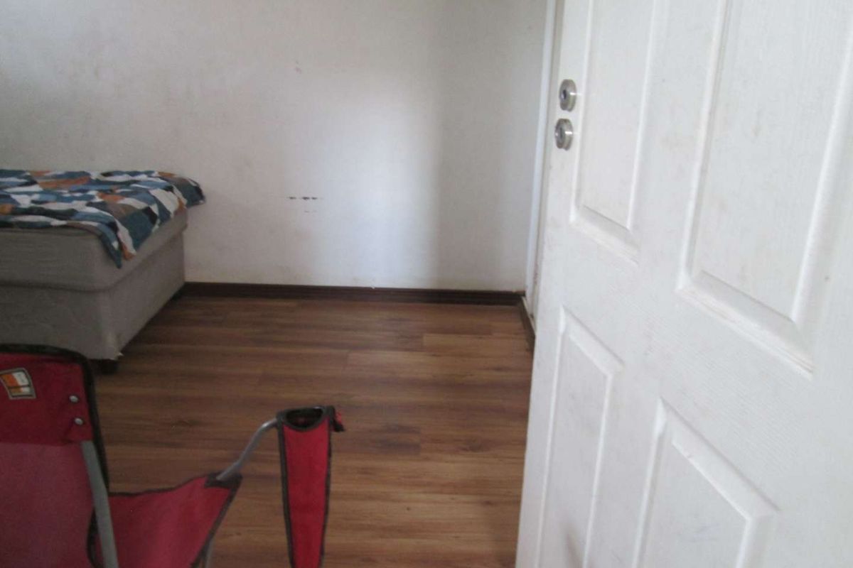 A bedroom featuring laminate wood flooring and a standard interior door.