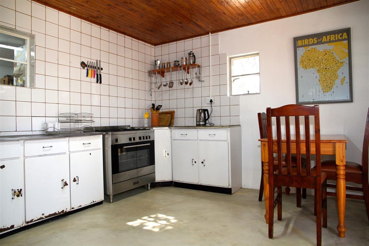 A functional kitchen featuring white cabinetry, a stainless steel freestanding stove, and tiled splashbacks, with an adjacent dining area.