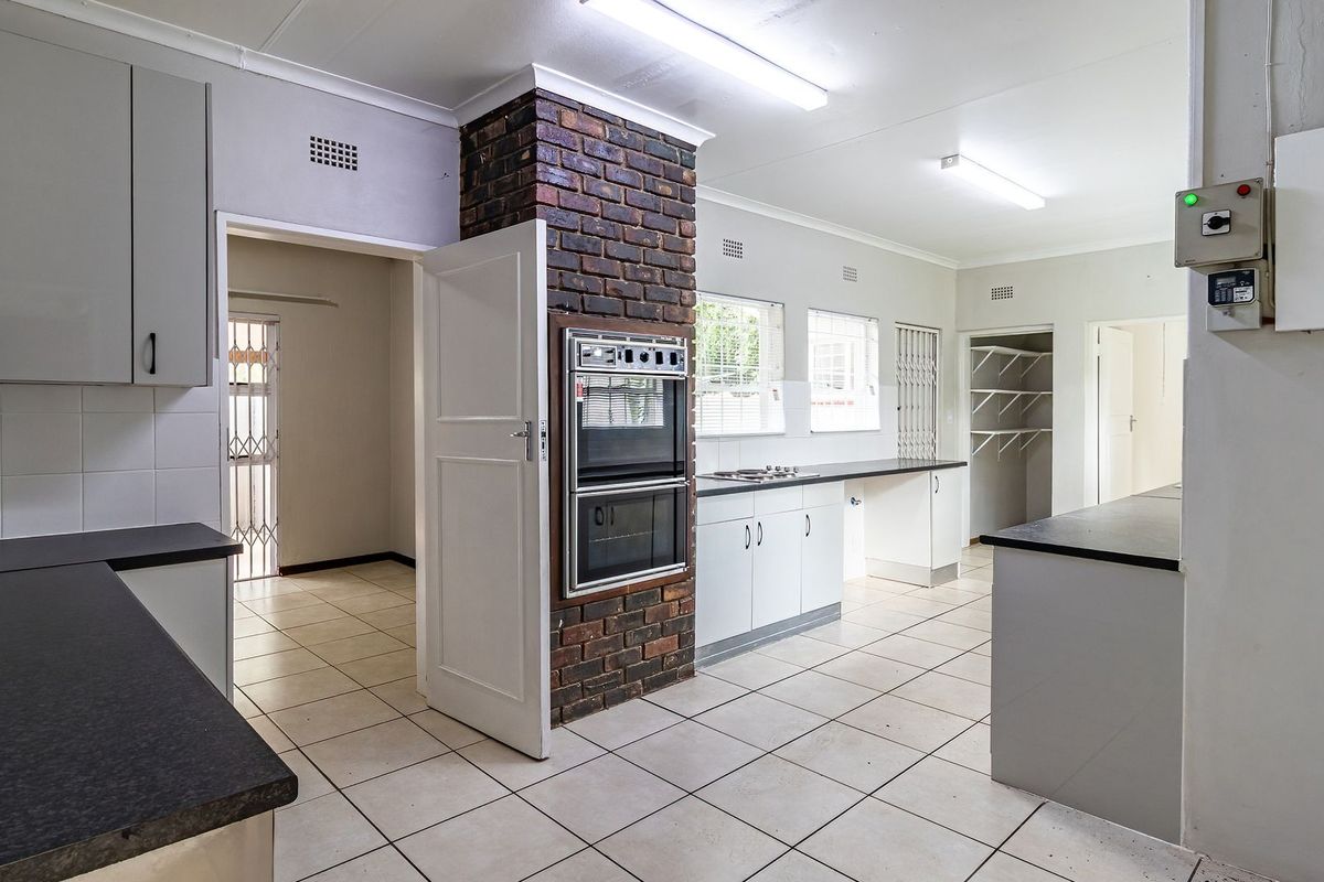 Spacious kitchen featuring a brick pillar with built-in double oven, ample cabinetry, tiled flooring, and an integrated pantry area.