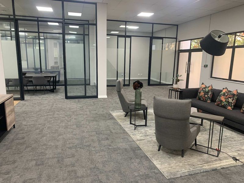 Modern open-plan office space featuring sleek black-framed glass partitions, recessed lighting, and professional carpeted flooring.