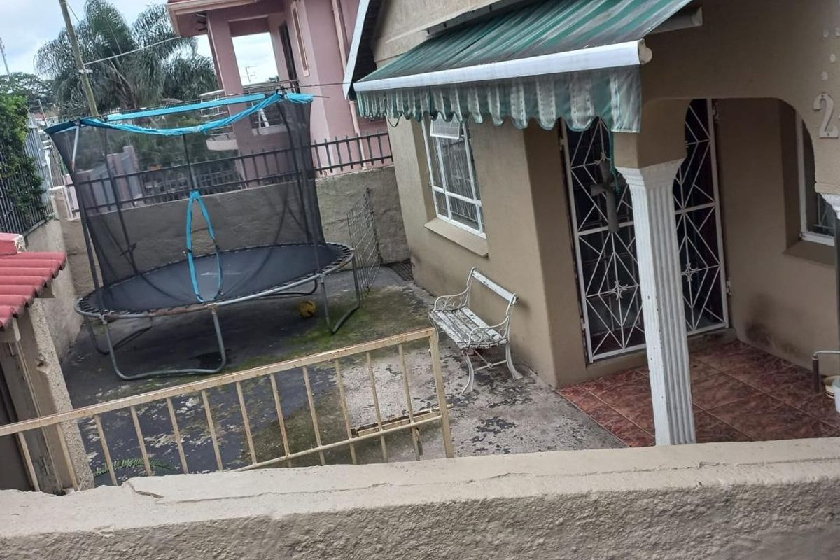 Front exterior view of the house featuring a small paved courtyard, security gate, and a retractable awning over the entrance porch.