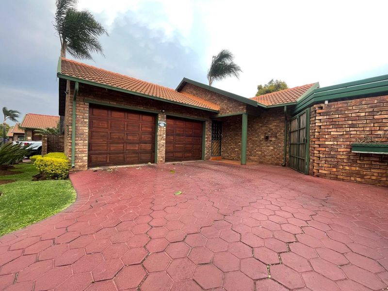 Front elevation of a brick house featuring a double garage, tiled roof, and a paved driveway.