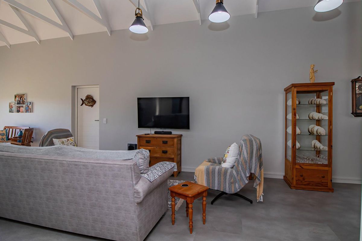 Spacious living area featuring high vaulted ceilings with exposed beams, modern pendant lighting, and neutral tiled flooring.