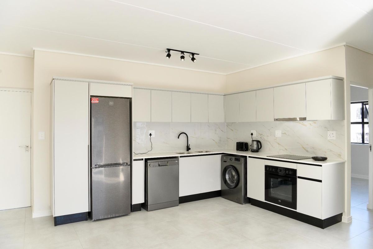 Modern kitchen featuring sleek white cabinetry, marble-look splashback, integrated oven, electric cooktop, and high-quality finishes throughout.