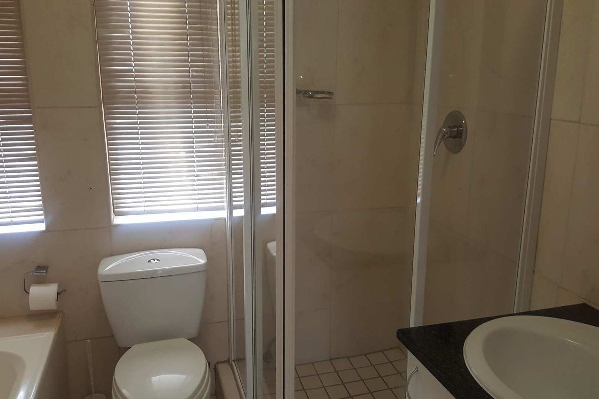 A functional bathroom featuring a built-in bathtub, a separate glass-enclosed shower, a toilet, and a vanity with a basin.