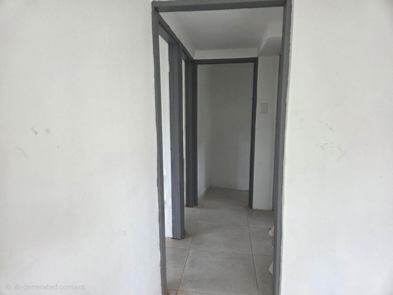 A vacant interior hallway featuring tiled flooring and painted door frames, showing signs of wear on the walls.