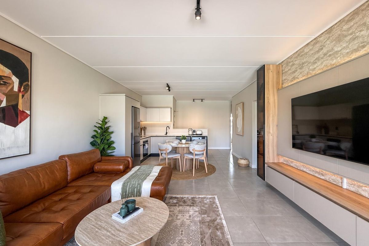 Modern open-plan living area featuring a sleek kitchen, tiled floors, and a custom built-in media wall with integrated lighting.