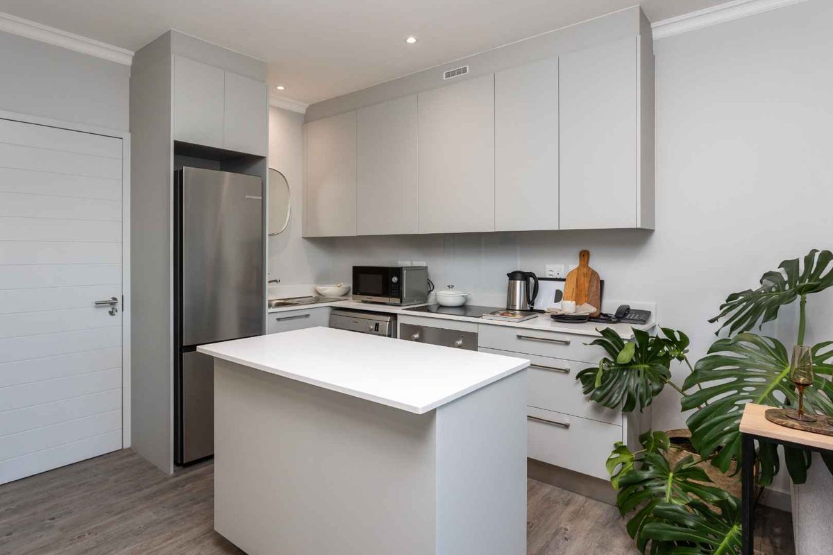 Modern kitchen featuring sleek grey cabinetry, a central island with a white countertop, and integrated appliances in a clean, contemporary layout.