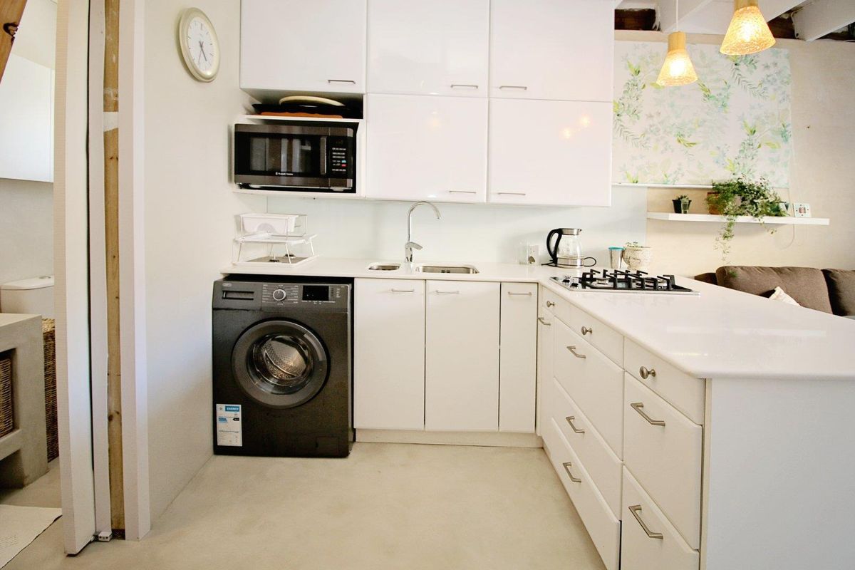 Modern kitchen featuring white cabinetry, integrated gas cooktop, built-in microwave, and a sleek countertop with an undermount sink.