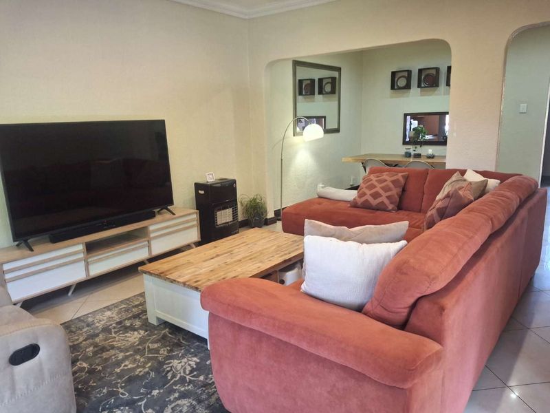 A comfortable living room featuring tiled flooring and an arched entryway leading to an adjacent dining area.