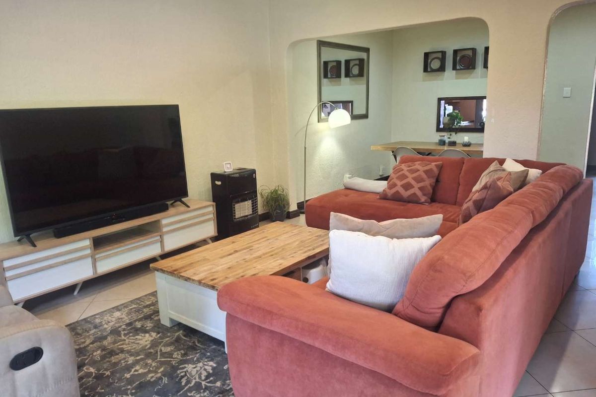 A comfortable living room featuring tiled flooring and an arched entryway leading to an adjacent dining area.