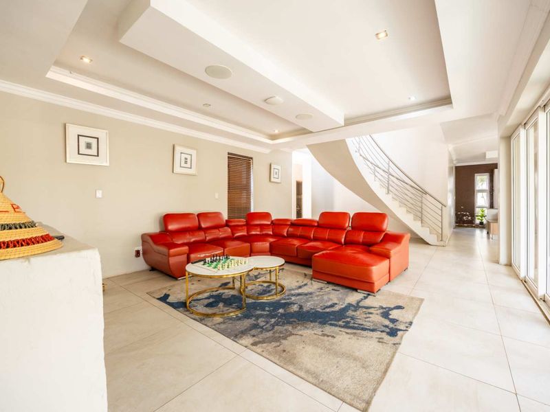 Spacious living room featuring a modern staircase with metal balustrade, recessed ceiling lighting, and large sliding glass doors leading to the exterior.