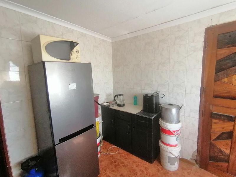 A small, dated kitchen area featuring tiled walls and flooring with basic built-in cabinetry, requiring modernization and improved layout.