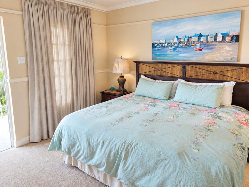 A comfortable bedroom featuring neutral wall tones, carpeted flooring, and a sliding glass door providing access to the exterior.