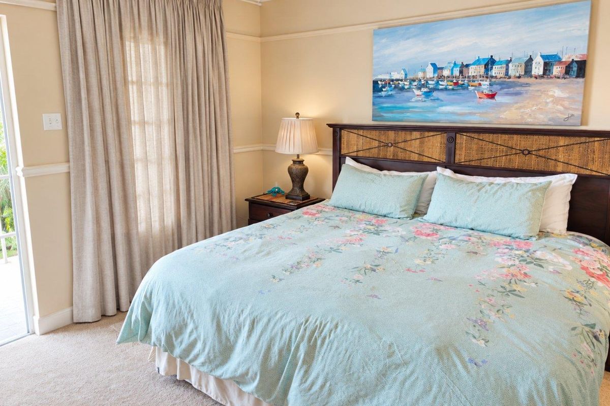 A comfortable bedroom featuring neutral wall tones, carpeted flooring, and a sliding glass door providing access to the exterior.